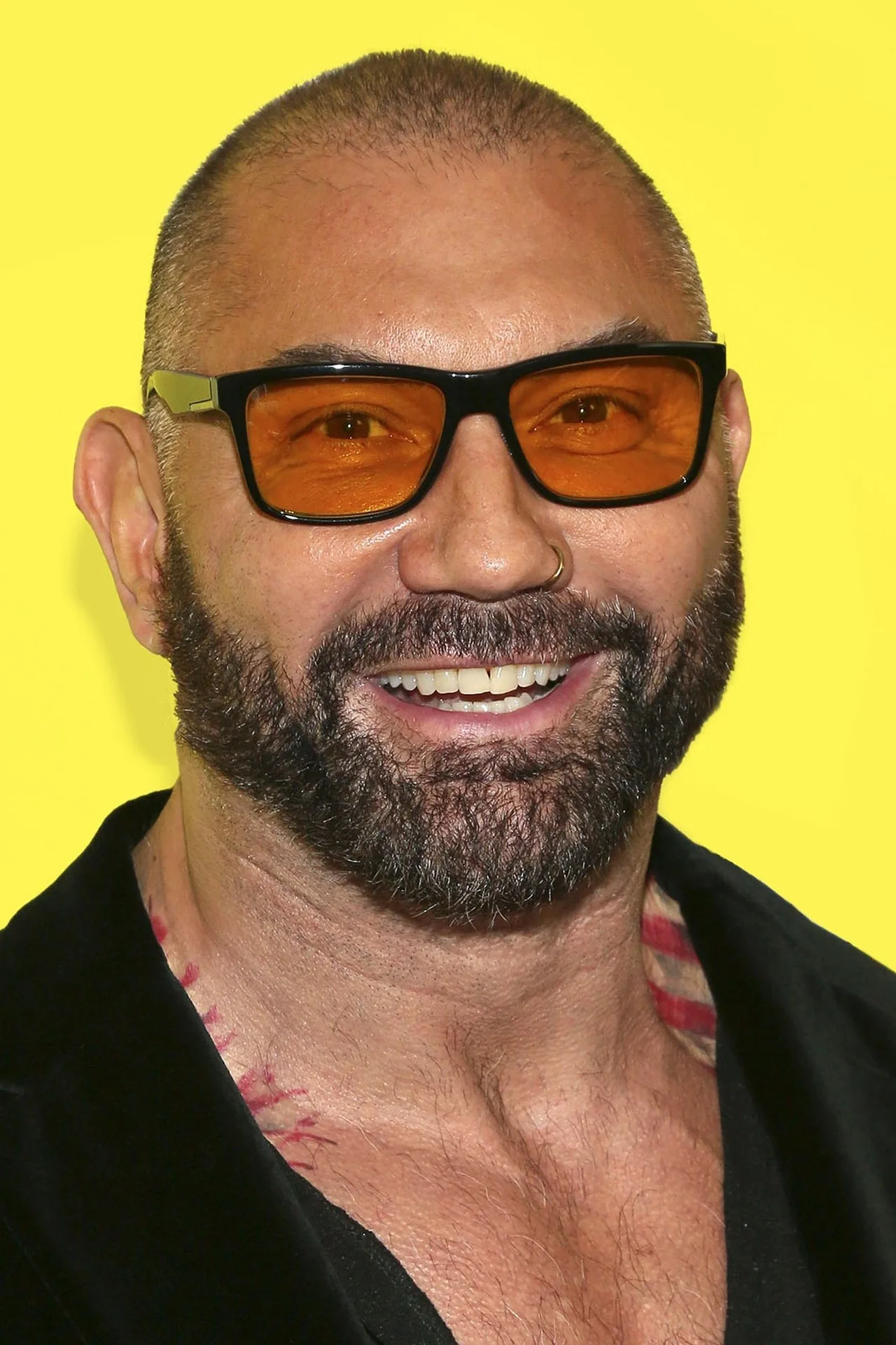 Bautista em traje de Kratos, segurando halteres, ao fundo escultura grega e bandeira da Amazon Prime