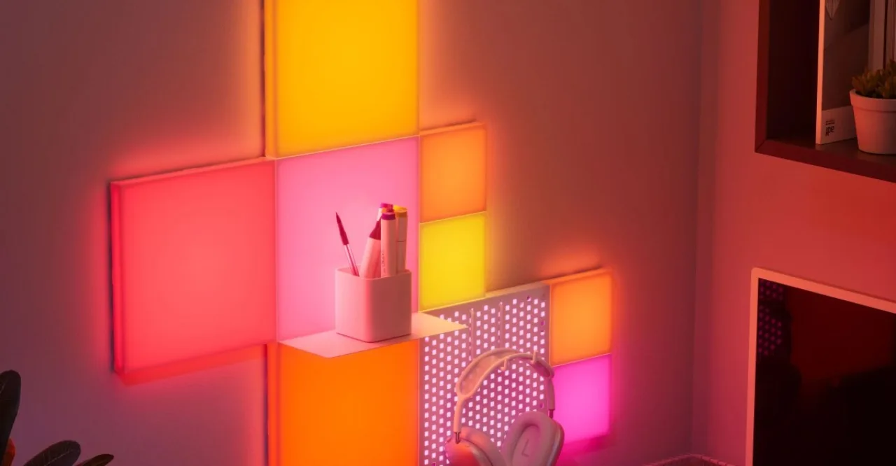 Jovem em pose de prancha sobre tapete, cercado por blocos de luz RGB Nanoleaf Combo XL em cores vibrantes