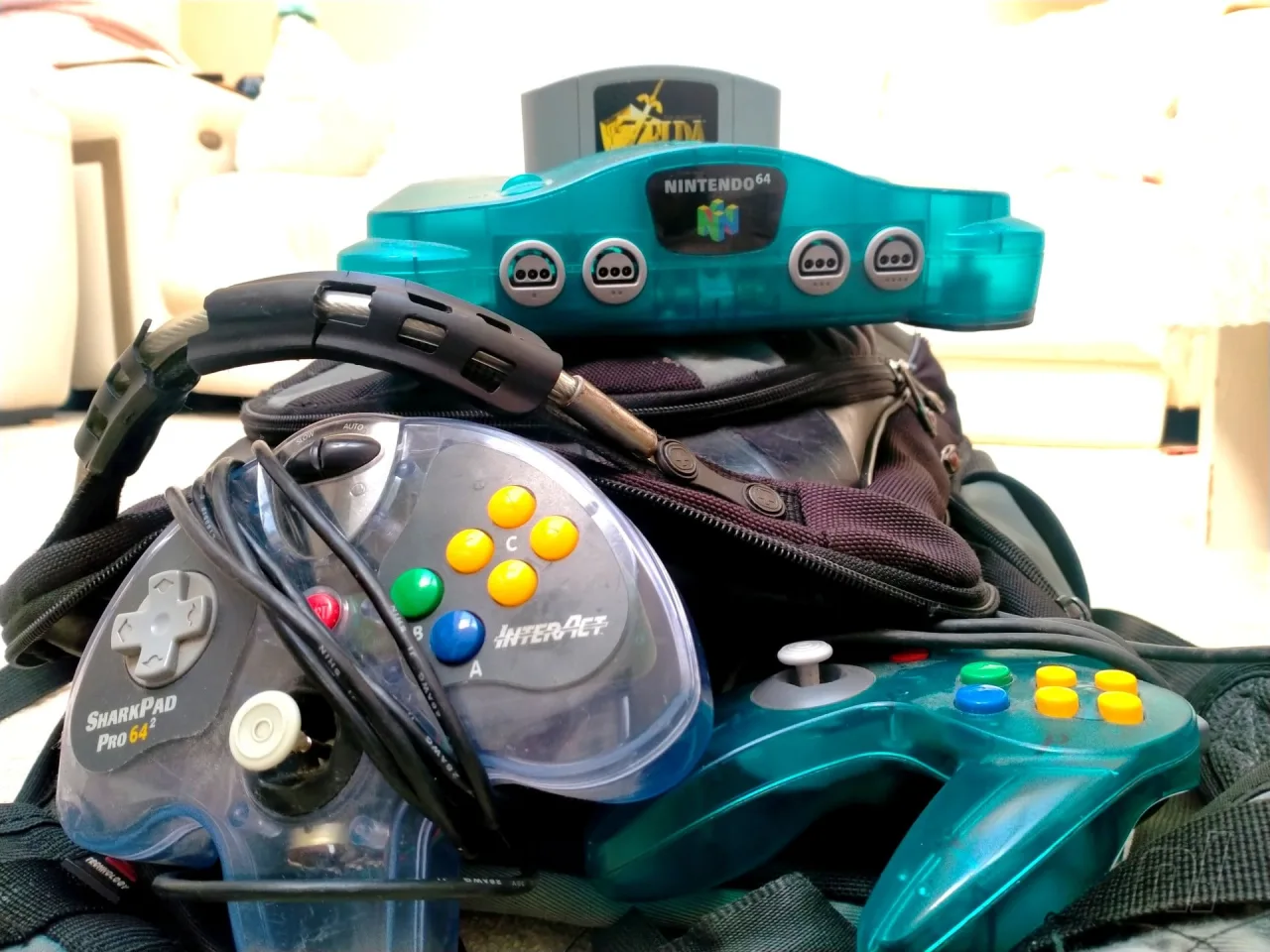 Jovem faz agachamento segurando o controle do N64, com console e TV ao fundo