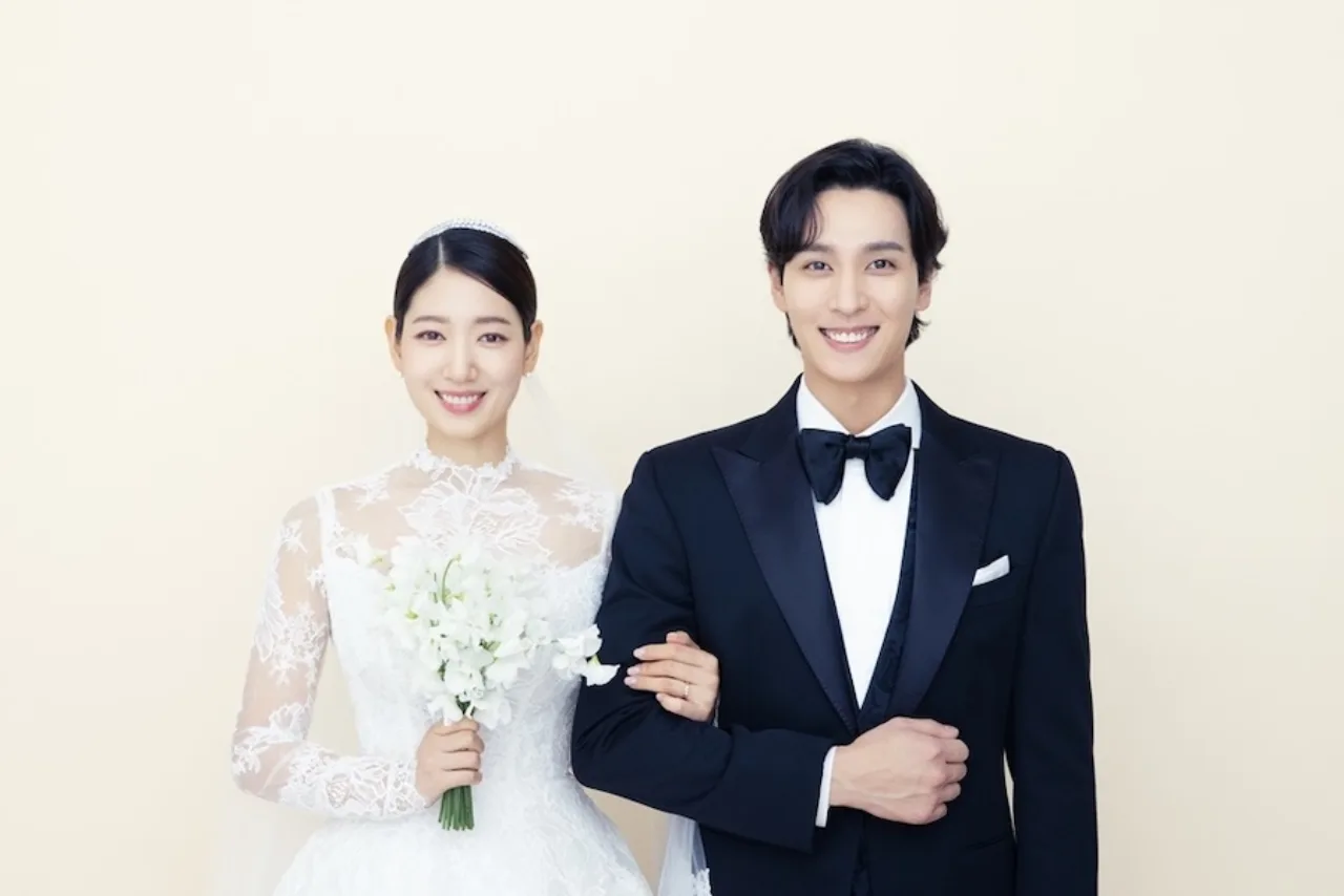 Park Shin Hye e Choi Tae Joon aparecem sorrindo, segurando a recém‑nascida segunda filha nos braços