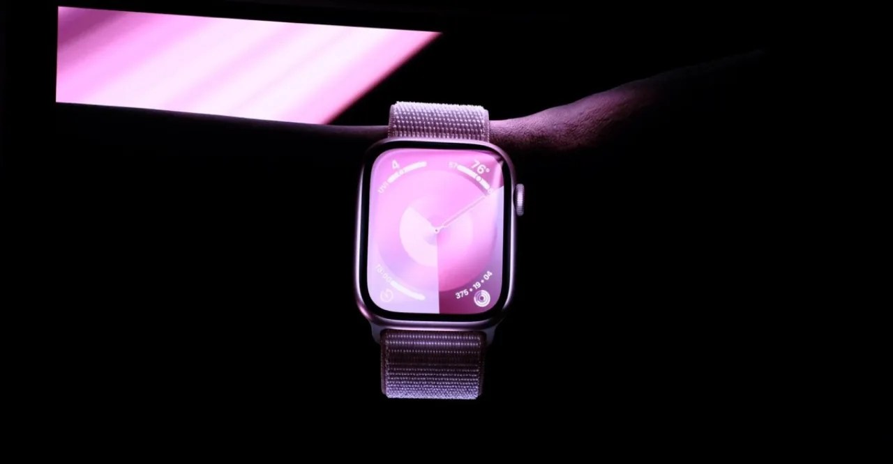 Corredor com Apple Watch 27 no pulso, segurando smoothie verde, fundo de academia moderna