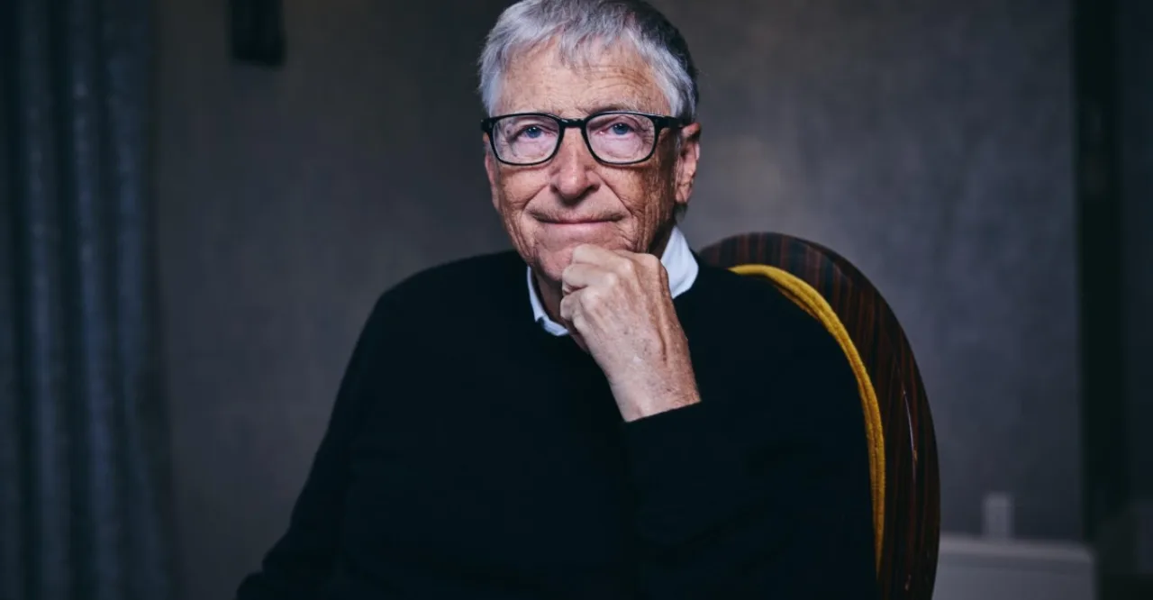 Bill Gates em estúdio, ao lado de holograma de cérebro digital e logo da Microsoft, falando sobre IA
