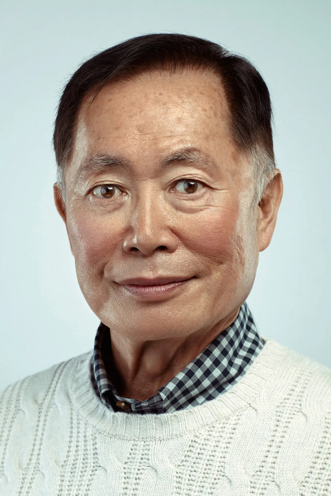 George Takei praticando esgrima com um florete ao lado de uma maçã e uma garrafa de água em um cenário futurista