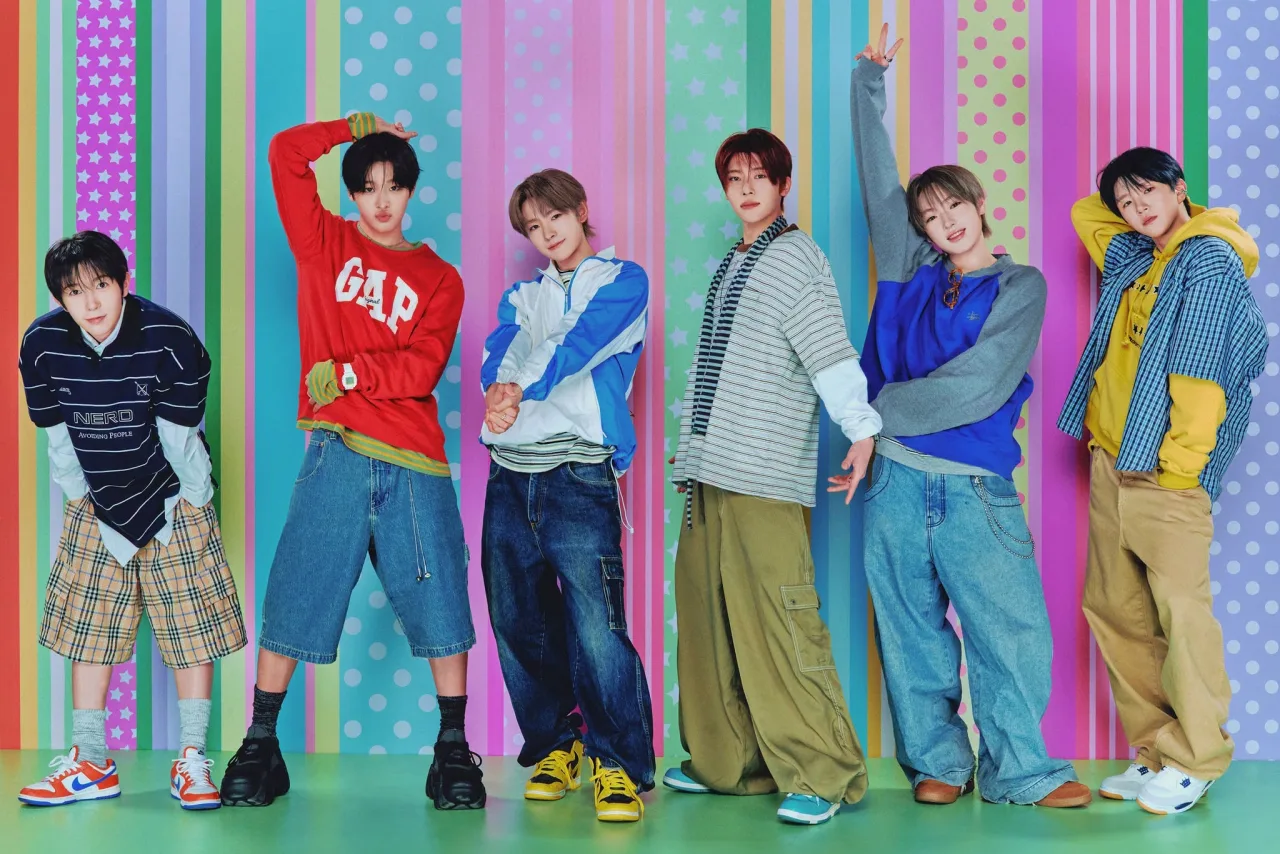 Membros de NCT WISH posam em trajes futuristas com o logo “I SPY” ao fundo, destacando o retorno em 12/10