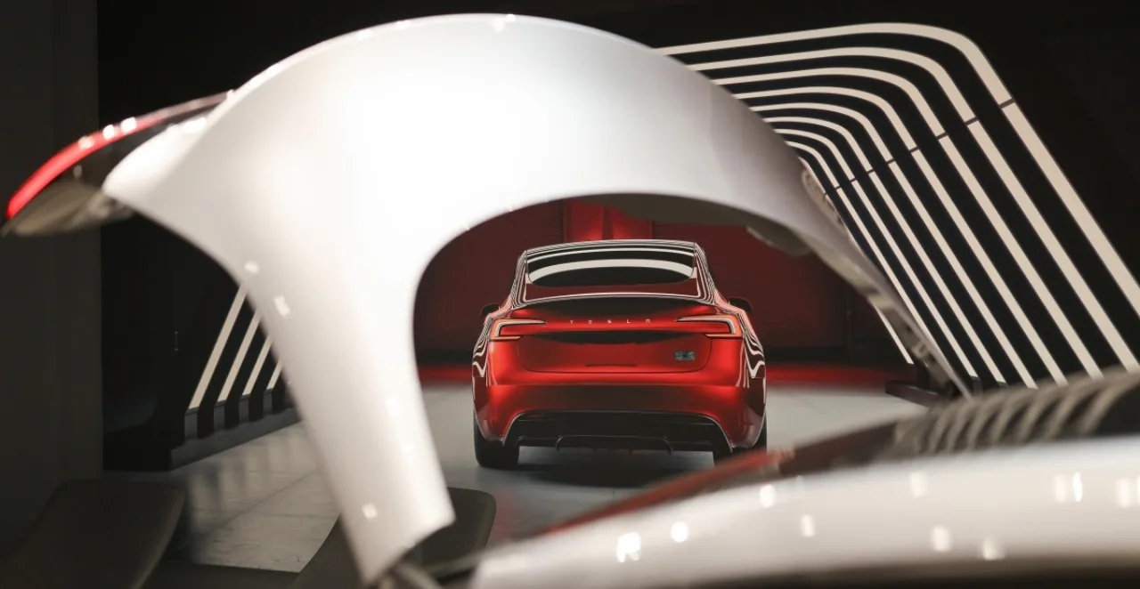 Logotipo da Tesla ao lado de um Model 3 vermelho estacionado, com gráfico de queda de entregas ao fundo