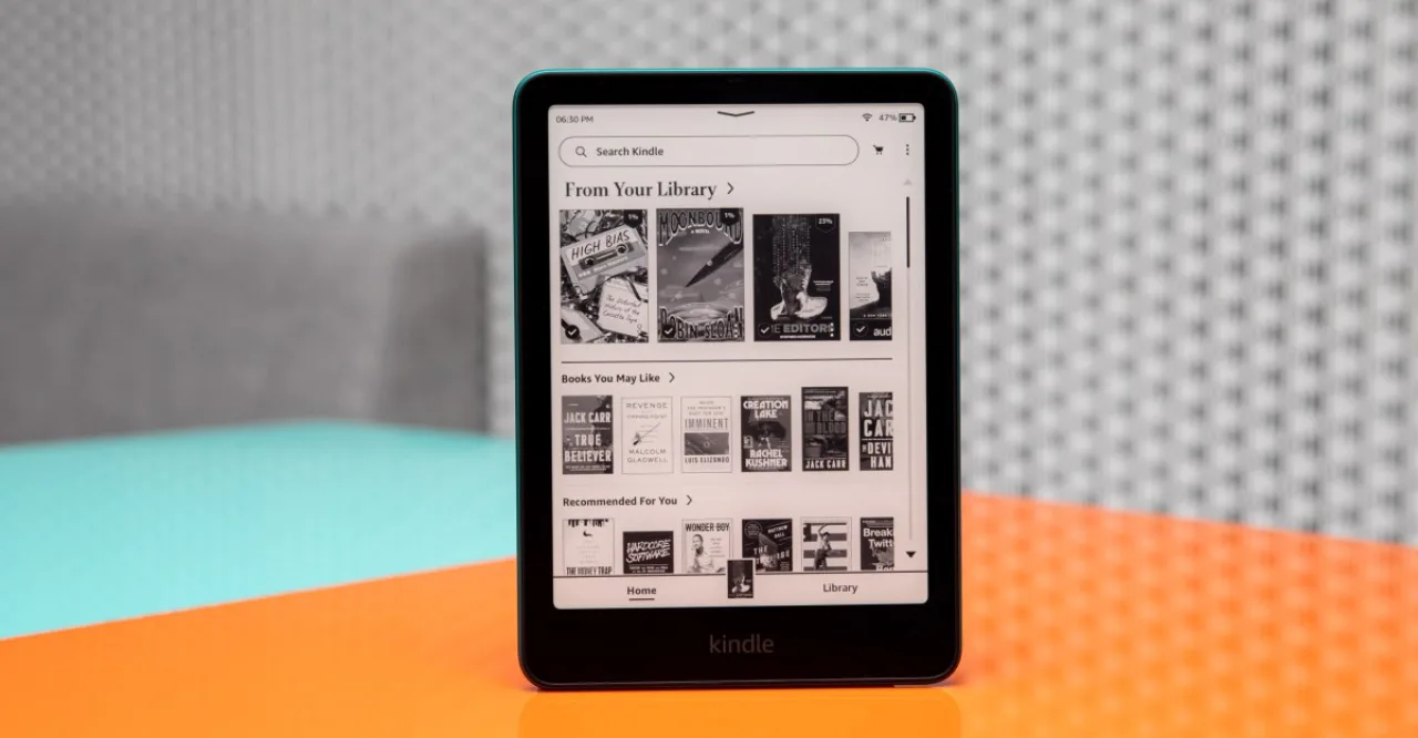 Um colecionador nerd segurando um Kindle prateado em uma mão e uma pilha de quadrinhos encadernados na outra