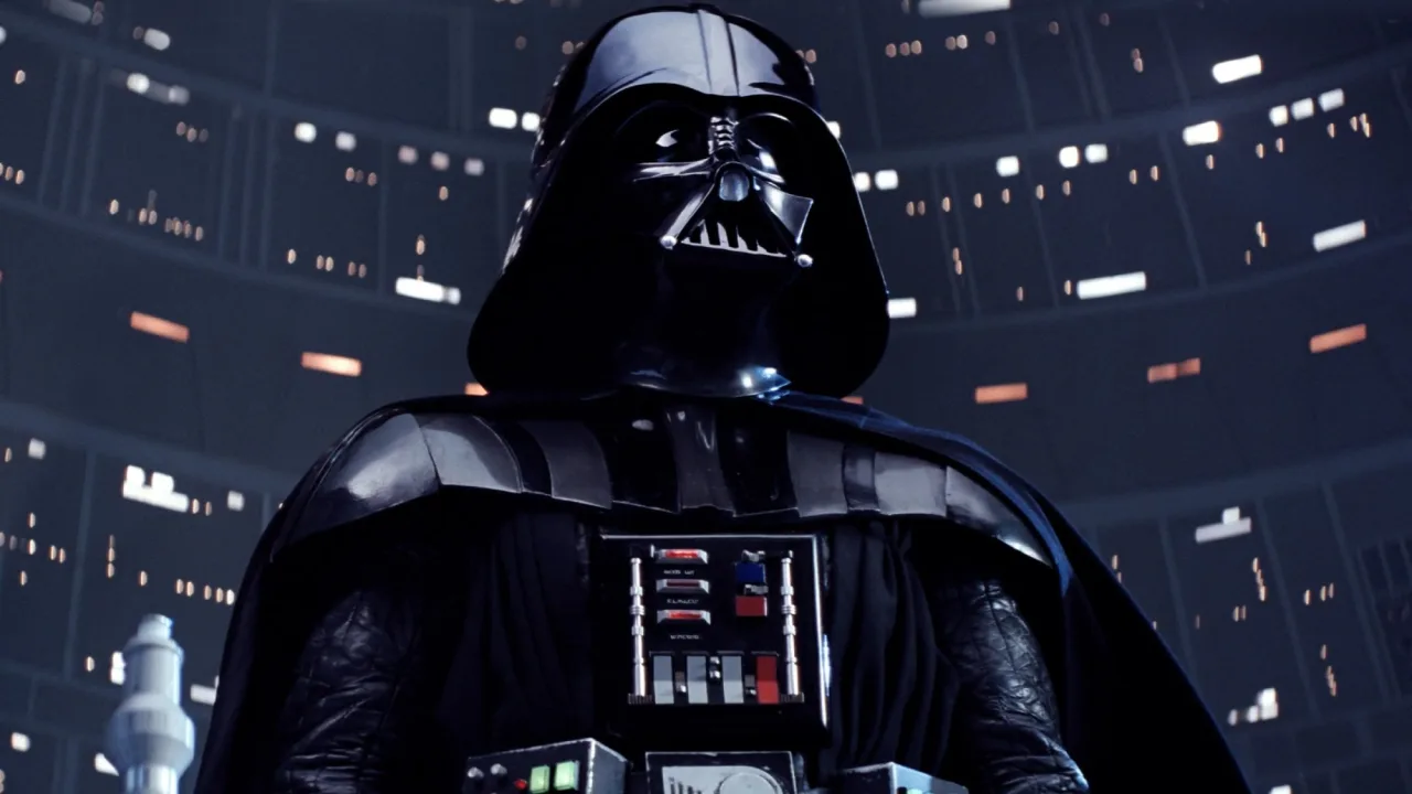 Colecionador musculoso segurando a figura vintage de Darth Vader ao lado de halteres