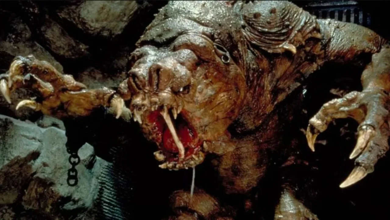 Colecionador faz agachamento segurando a figura Rancor da Kenner ao lado de halteres