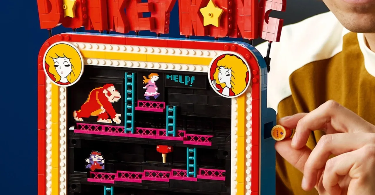 Mario de miniatura da LEGO pulando sobre barris coloridos ao lado de uma máquina arcade de Donkey Kong