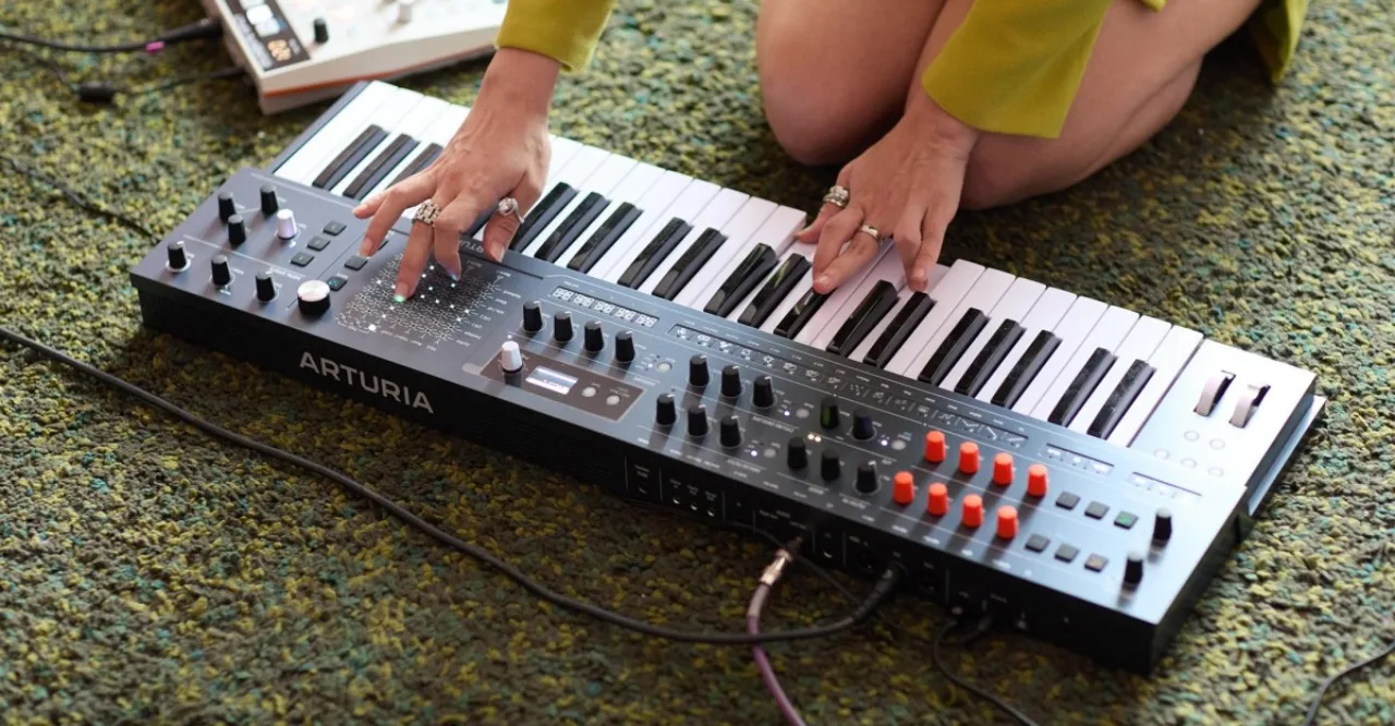 MiniFreak 49 da Arturia em destaque, com 49 teclas, painel de knobs e tela digital, ao lado do logotipo da marca