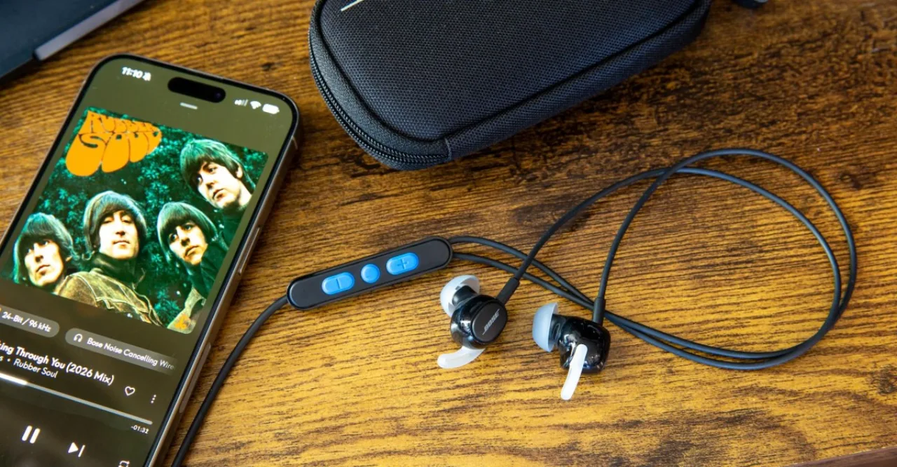 Earbuds Bose pretos com cabo e logotipo ao lado de um smartphone sem Bluetooth, destacando a conexão física