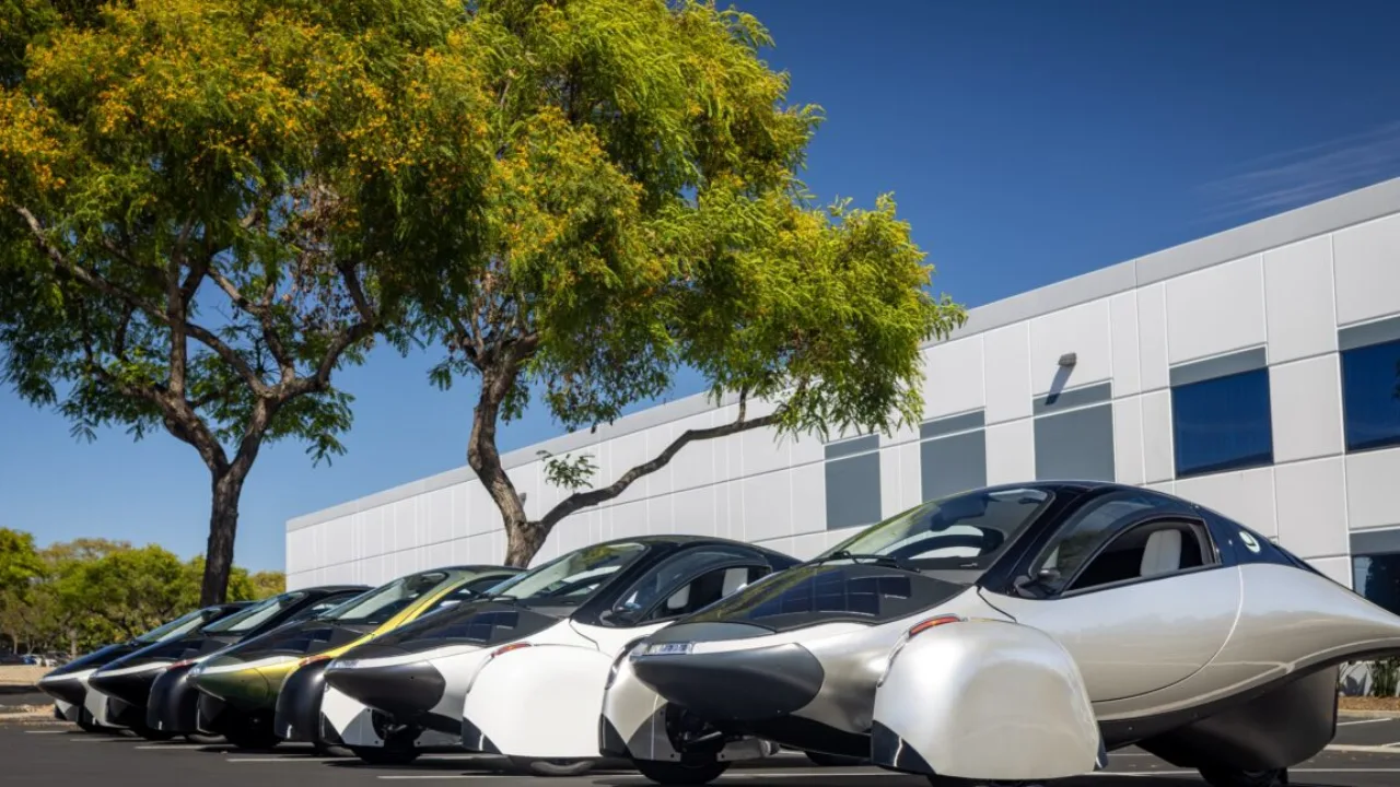 Carro solar de três rodas com design aerodinâmico estacionado em uma instalação de montagem moderna e iluminada