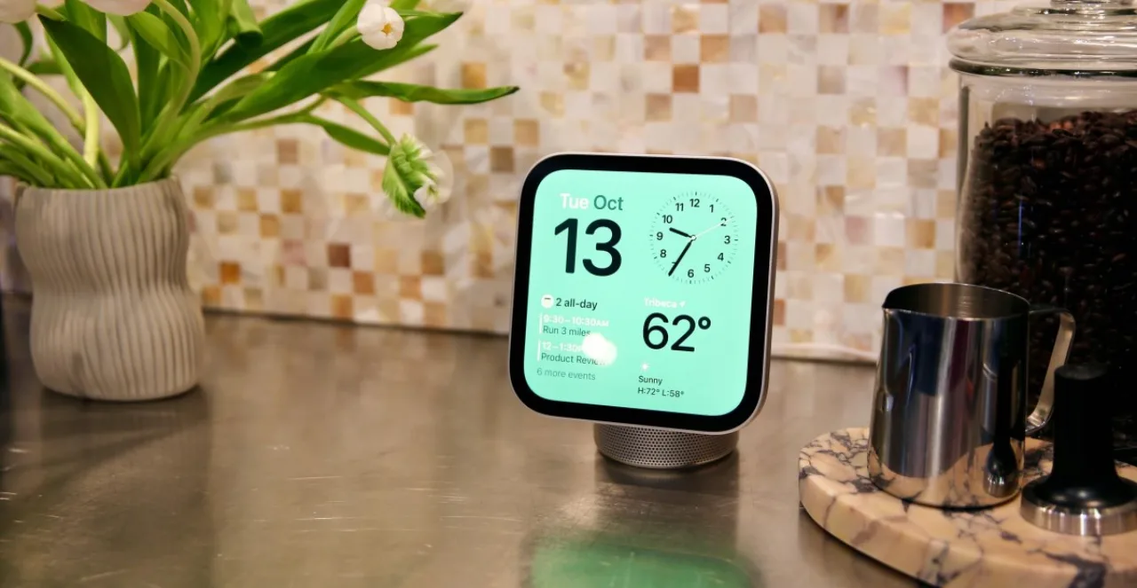 Smart display Apple HomeView sobre mesa de madeira, exibindo tela minimalista com ícones de casa inteligente e logo da Apple