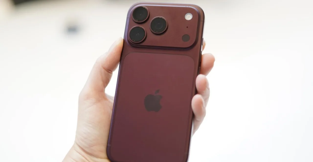 iPhone 18 Pro prateado sobre mesa de vidro ao lado do logo da Apple, com o Apple Park ao fundo