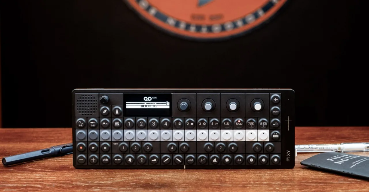OP-1 da Teenage Engineering sobre mesa, ao lado do logotipo da marca