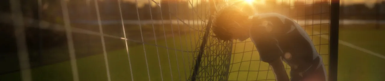 Jogador de futebol em campo, vestindo chuteira, driblando bola enquanto suga água de uma garrafa esportiva