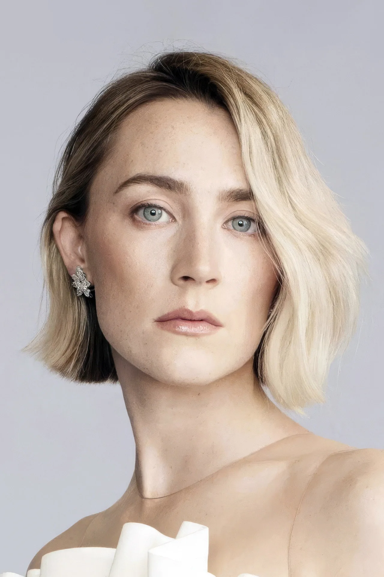 Saoirse Ronan em roupa de treino preta, segurando kettlebell dourado, ao fundo pôster de James Bond e cronômetro digital