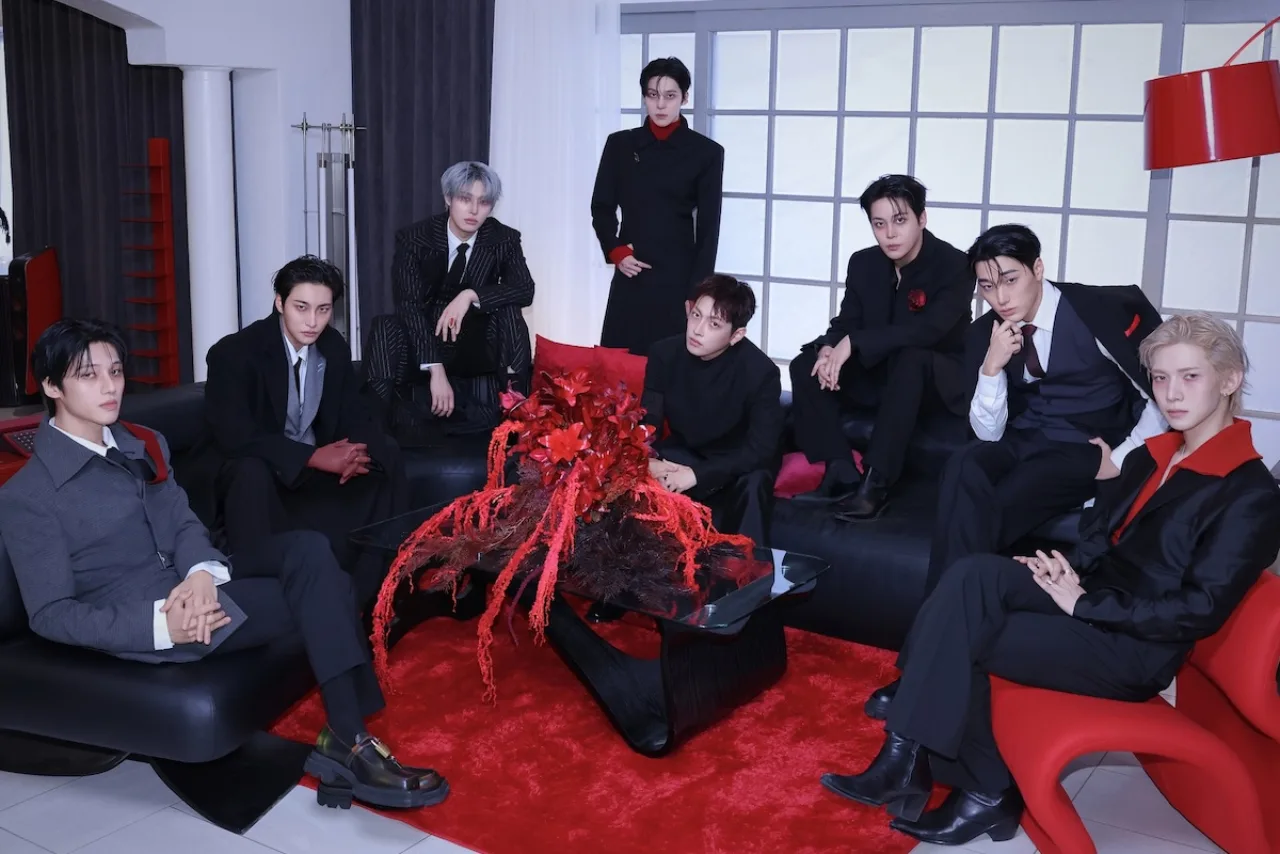 Membros da ATEEZ posam juntos, ao fundo o logo da turnê “ZERO TO ALL 2027” sobre um mapa-múndi estilizado