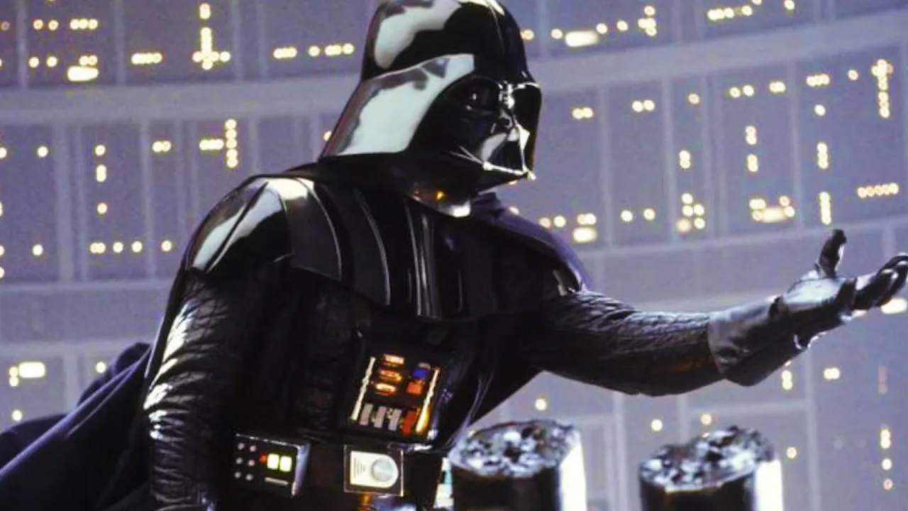 Um homem musculoso levanta a figura de Darth Vader como haltere, enquanto ao fundo há caixas de colecionáveis