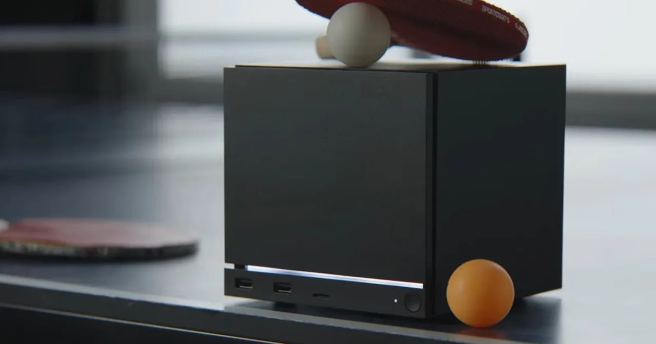 Um gamer sentado em poltrona, segurando controle do Steam Machine, ao lado de halteres e garrafa de água