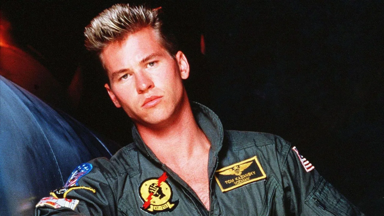 Capacete Iceman de Top Gun, com máscara de oxigênio e mangueiras, sobre fundo escuro ao lado do logotipo do filme