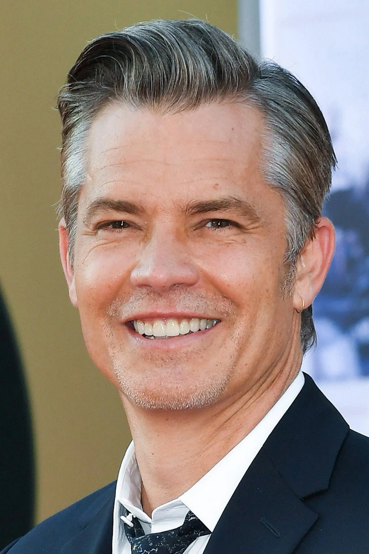 Timothy Olyphant faz treino ao ar livre, correndo ao lado de três filhos, vestindo shorts e camiseta esportiva