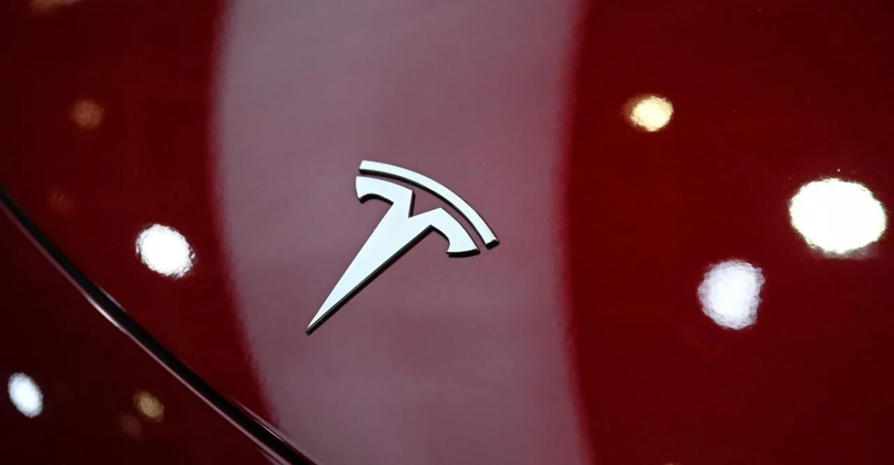 Homem de 40 anos vestindo roupa esportiva, smartwatch no pulso, ao lado de um Tesla Model 3 estacionado