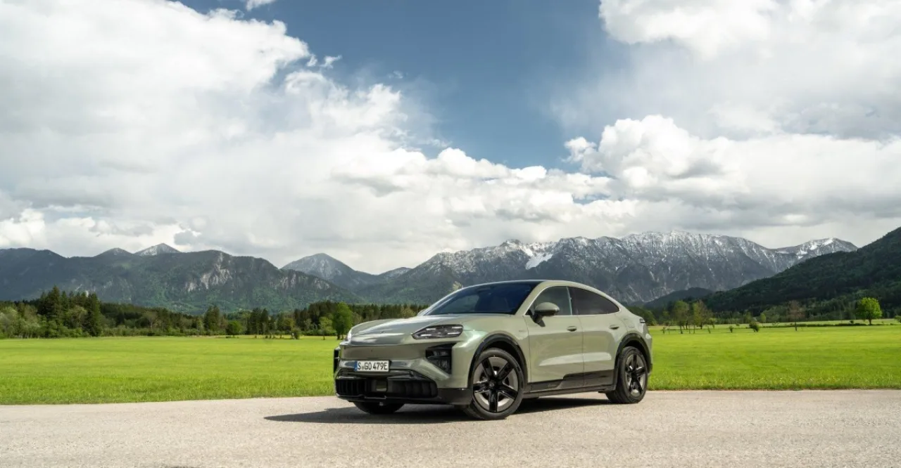 Atleta em traje esportivo correndo ao lado do Porsche Cayenne Coupe Turbo em pista de asfalto