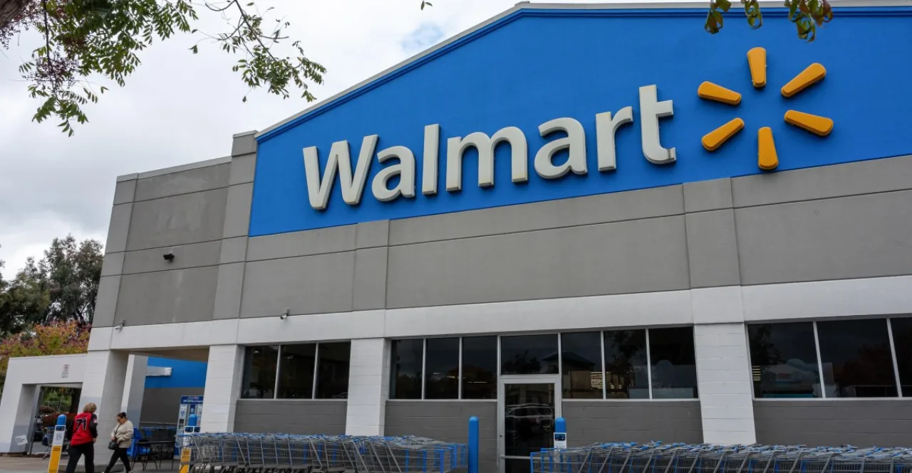 Jovem em roupa de academia usando Apple Pay no caixa do Walmart, ao lado de sacolas com frutas e legumes