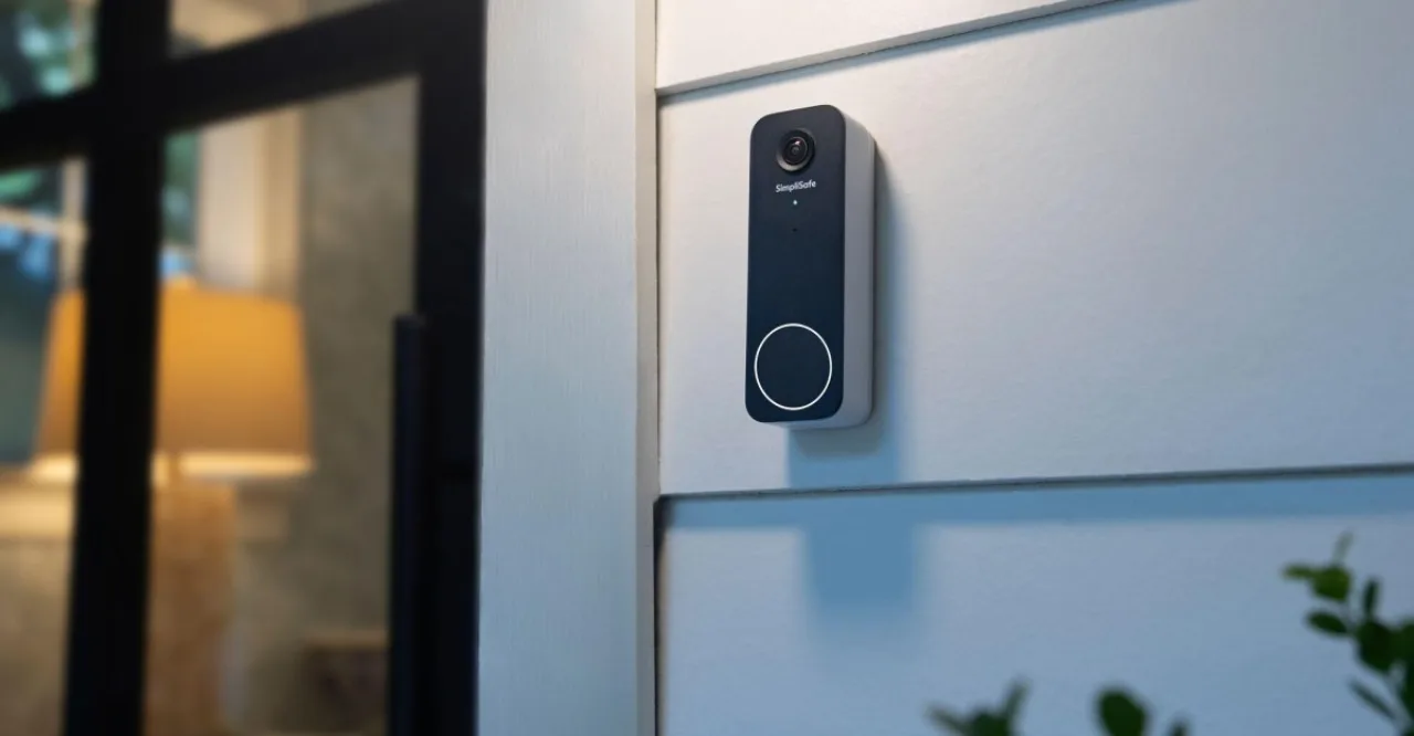 Campainha inteligente SimpliSafe Video Doorbell Series 2 instalada na porta, com logo da marca e tela de smartphone exibindo vídeo ao vivo