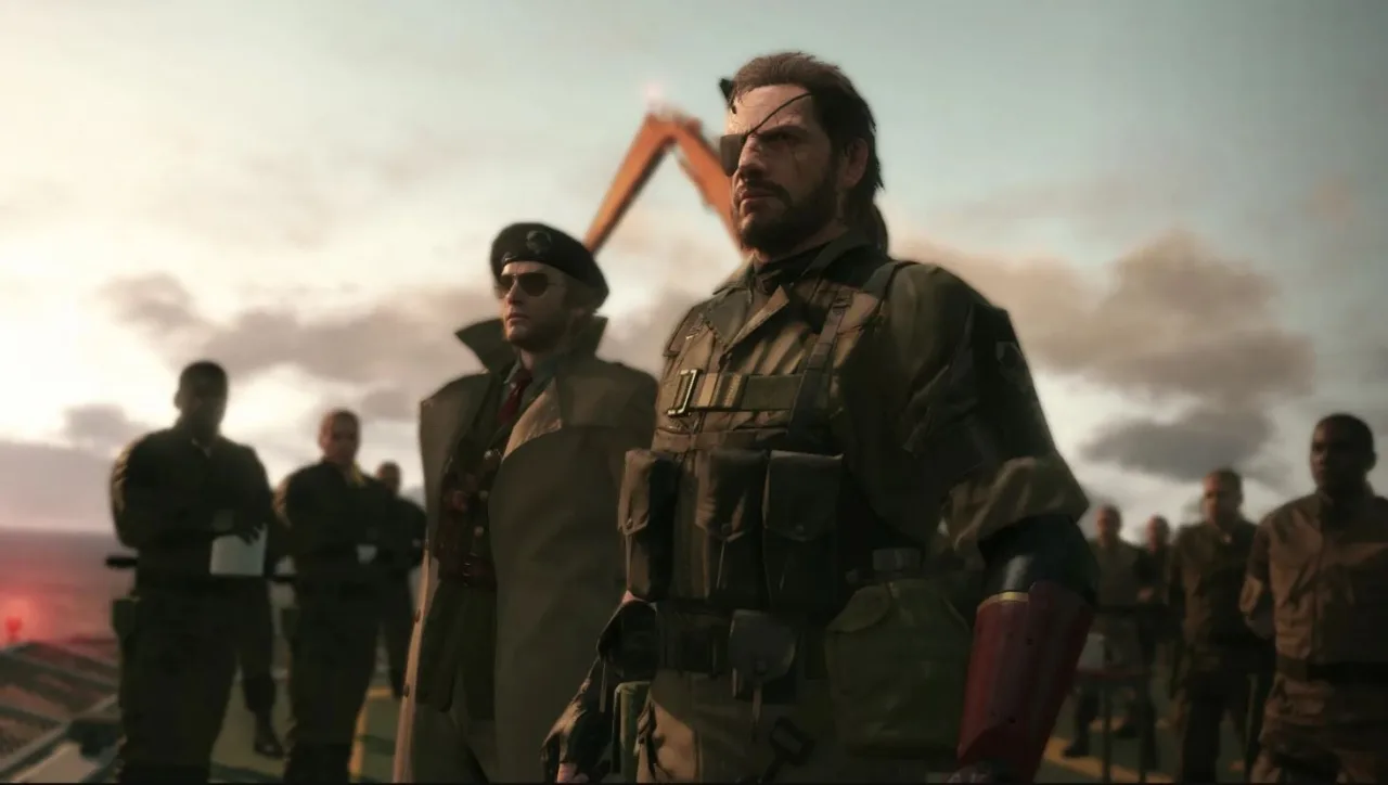 Akio Otsuka em estúdio, microfone à frente, ao fundo o logo de Metal Gear e a silhueta de Solid Snake