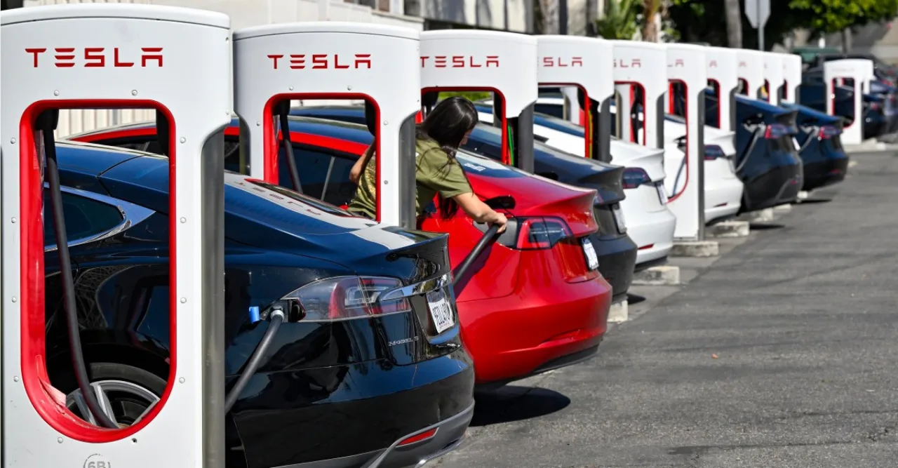 Tesla Model 3 estacionado em Supercharger, motorista saindo do carro com o cabo ainda conectado