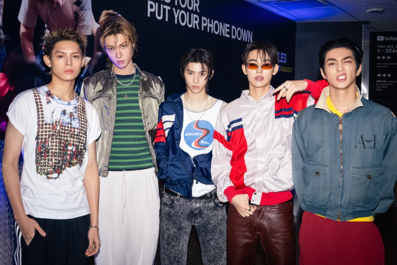 Logo da BIGHIT MUSIC ao lado da fachada de uma casa, com distintivo policial sobreposto