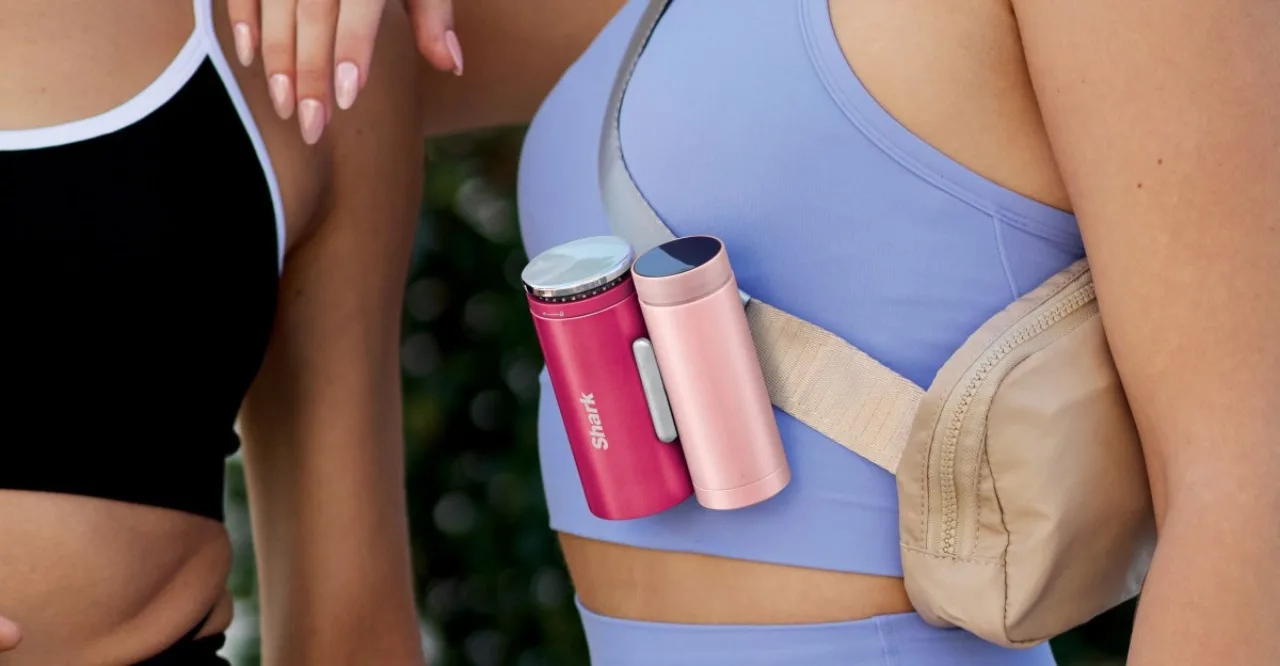 Corredor em roupa esportiva, suando, segurando o Shark ChillPill ao lado, borrifando água enquanto corre ao ar livre