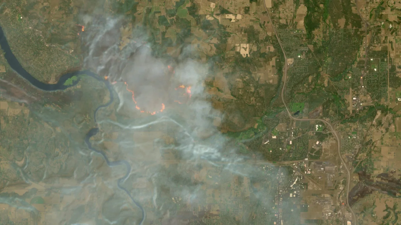 Mapa satélite Sentinel‑2 mostrando floresta em chamas, fumaça densa e áreas carbonizadas em tons avermelhados