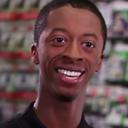 Jovem gamer sentado, usando headset, fazendo pausa para alongamento de braços ao lado de um PC com Windows 11
